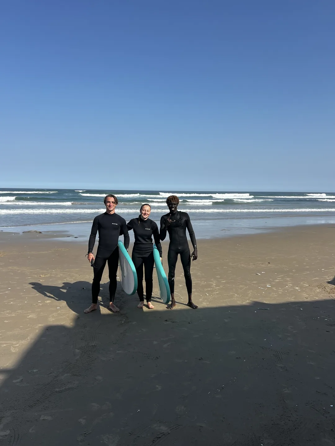 Trois surfeurs prêts à s'élancer sur les vagues au Sénégal.