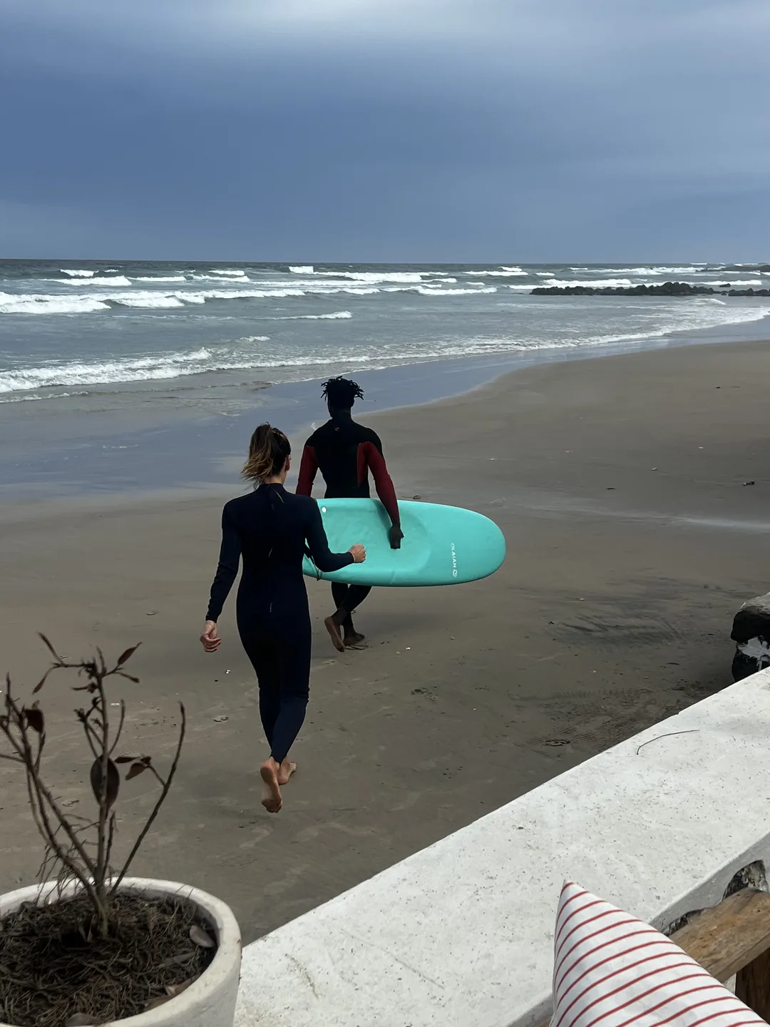 Deux surfeurs marchent vers l'océan sur la plage de l'île de Ngor au Sénégal.