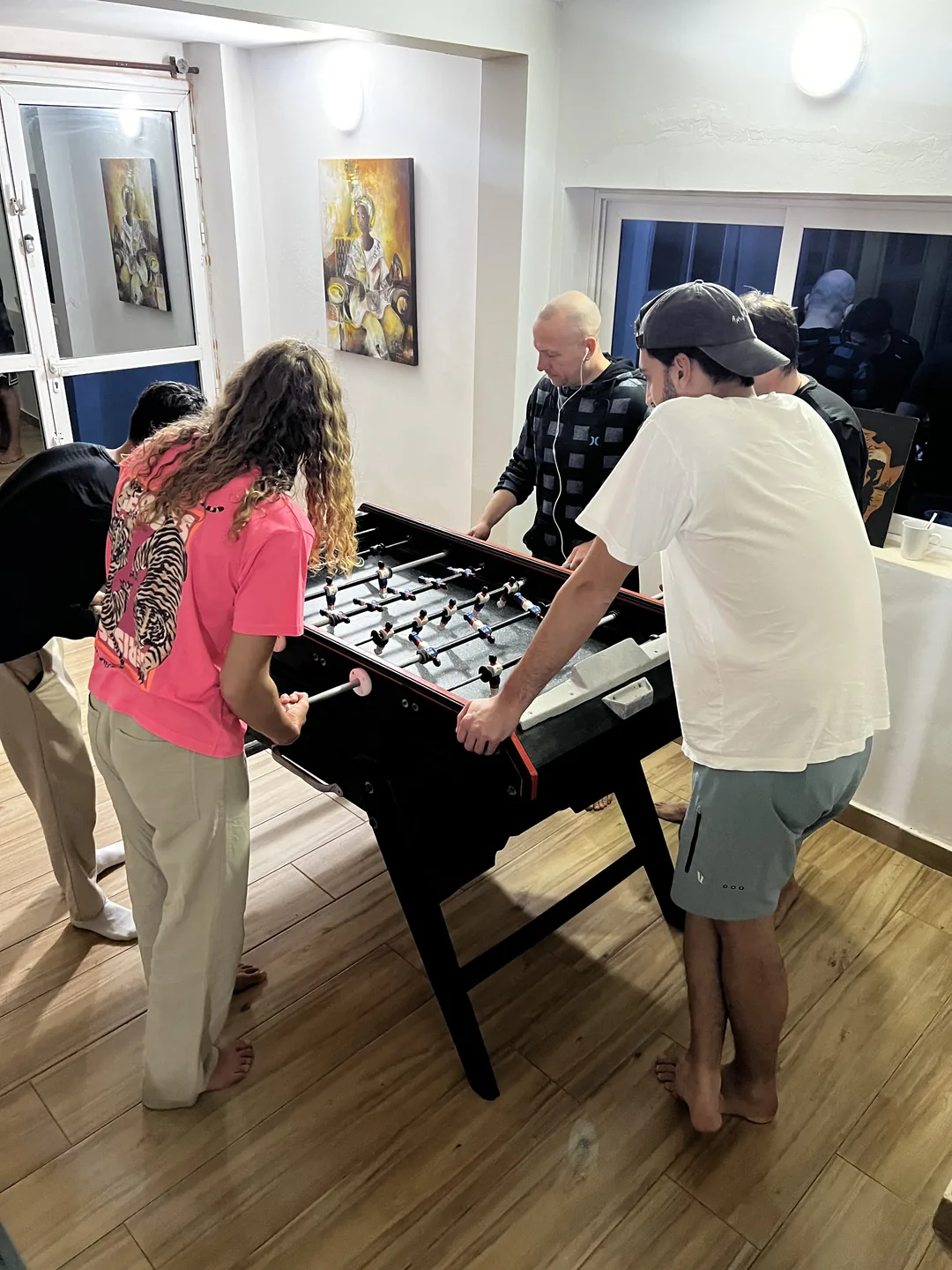 Des vacanciers s'amusent autour d'une table de baby-foot dans un surf camp.