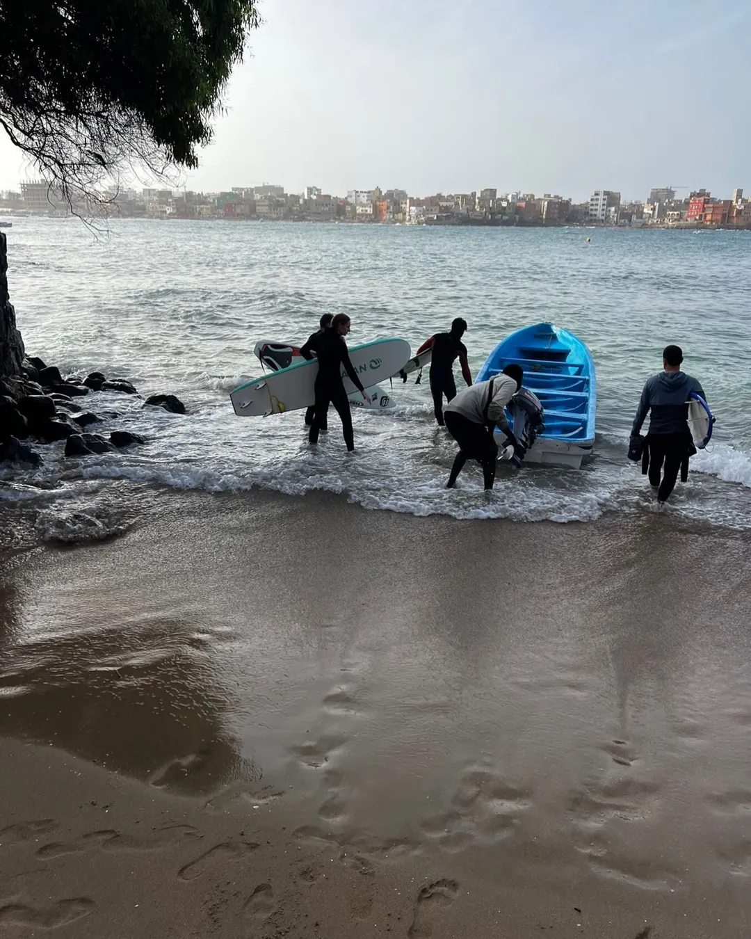 Surfers paddling out with Dakar skyline