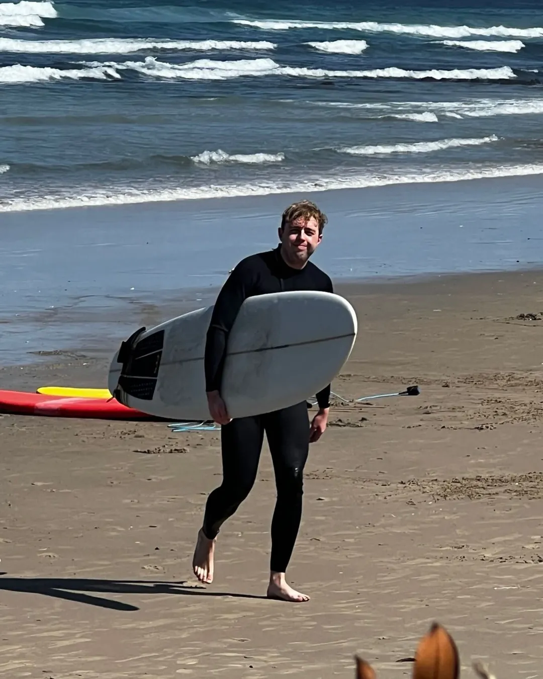 Smiling surfer holding board after a session