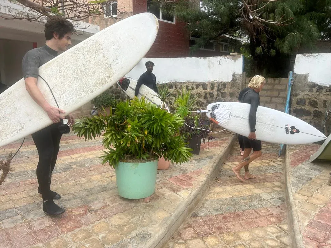 Surfers carrying boards at Ngor Surfcamp.