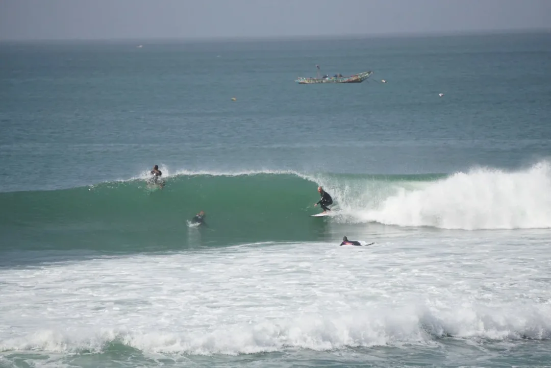 Surfers riding waves at Ngor Island.