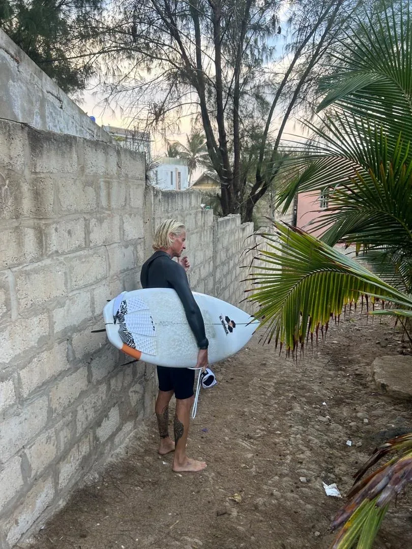 Surfer with board on Ngor Island path.