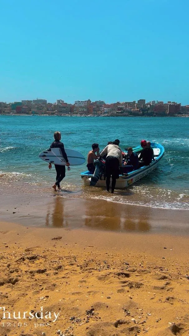 Surfers boarding a boat on Ngor Island beach.