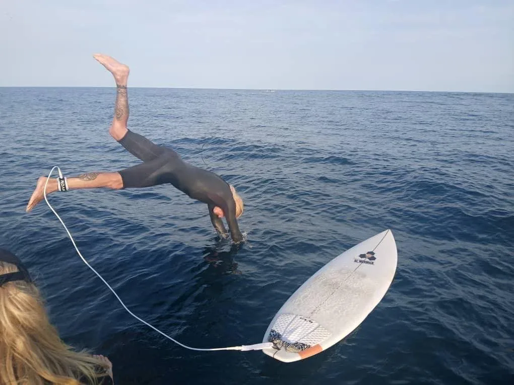 Surfer on a wave with a fishing boat at Ngor