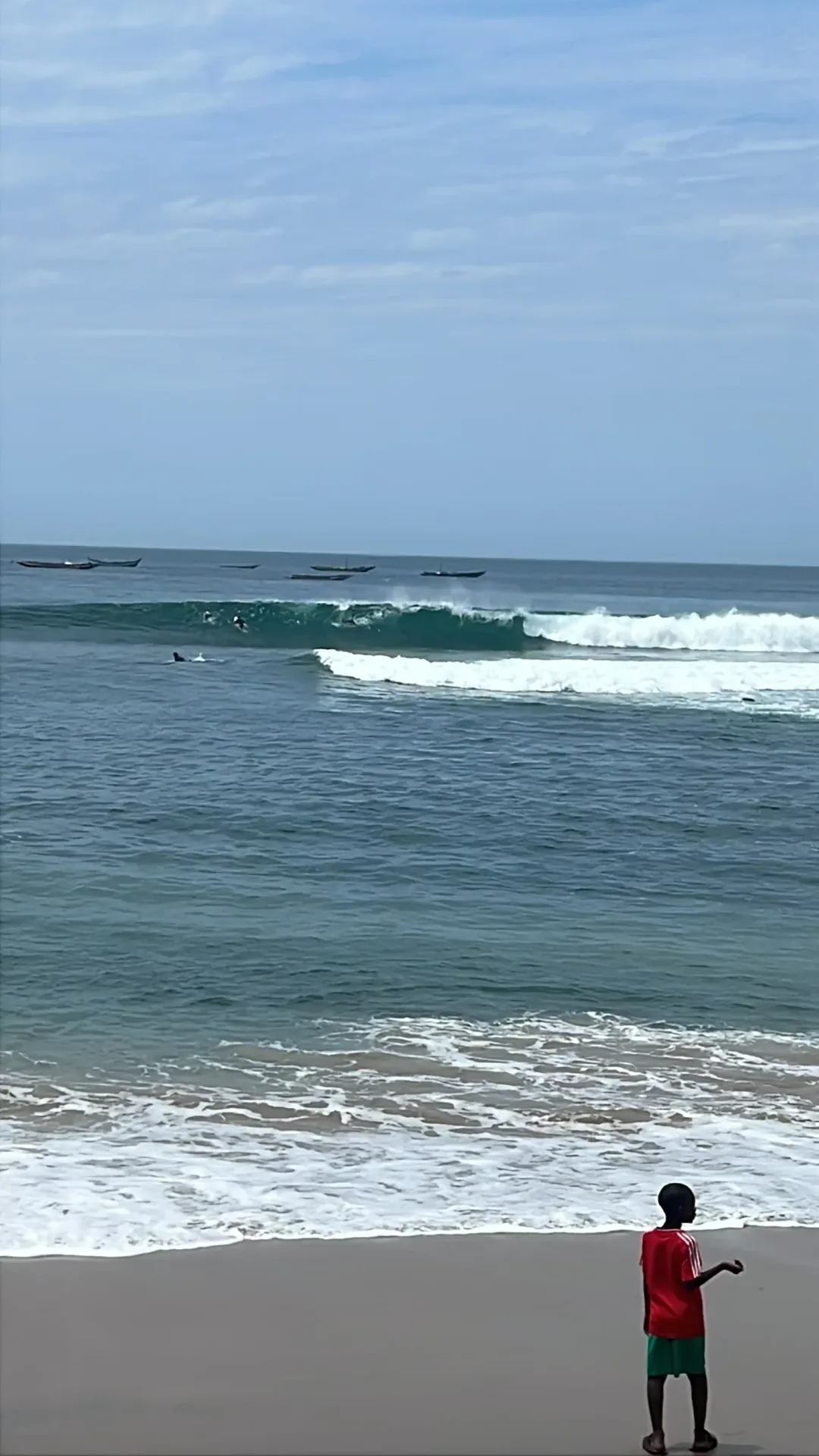 Beach view with waves and distant surfers.