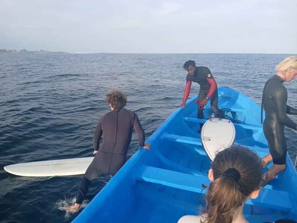 Surfers prepare for a session from a boat.