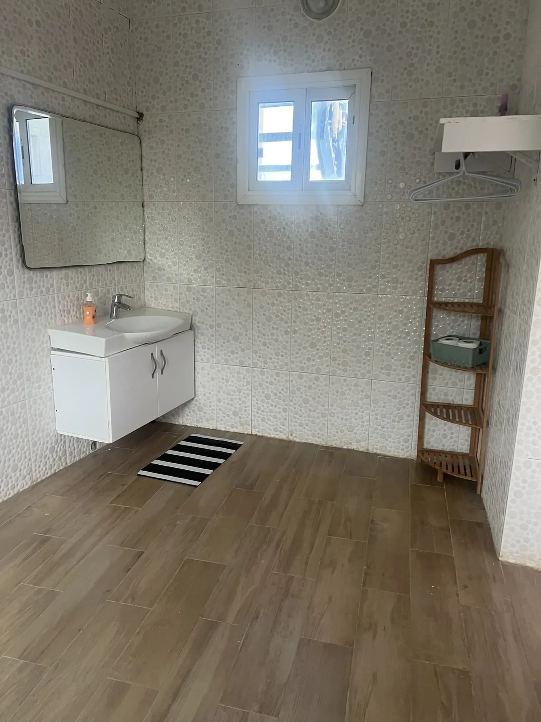 Simple bathroom with wooden floor and window.